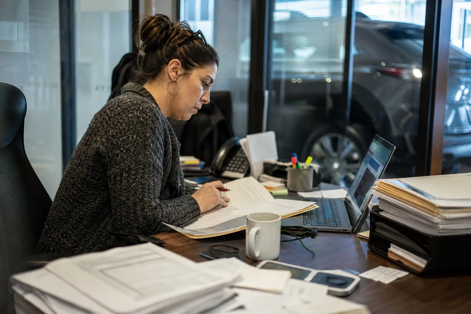 Compliance officer comparing a customer file with screening results at her desk